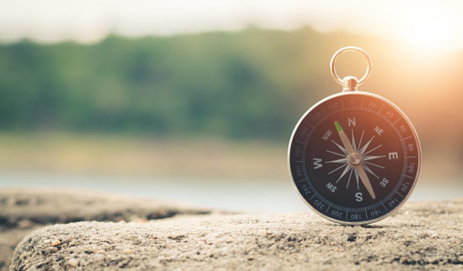 Compass of tourists on mountain at sunset sky.